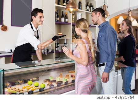 Man seller serving visitors in cozy pastry store 42621764