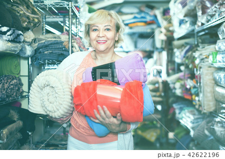 Adult female buyer choosing colour plaids in the textile store 42622196