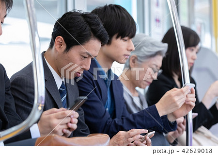 電車 車内でスマホ 携帯電話を操作するの写真素材