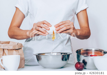Woman wearing white t-shirt breaking egg  42630181