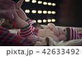 Cute baby boy dressed in striped christmas clothes is lying on beige bed and smiling while mother 42633492