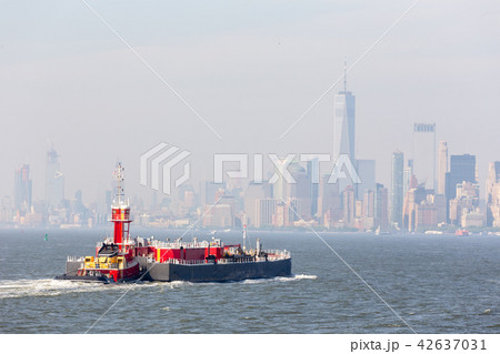 Freight tug pushing cargo ship to the port in New York City and Lower Manhattan skyscarpers skyline 42637031