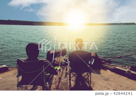 rear of two men on seat with fishing on pier rear of two men on seat with fishing on pier 42644241