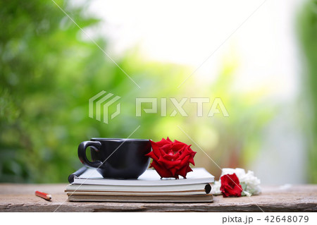 Black cup with red rose and notebook diary Black cup with red rose and notebook diary 42648079