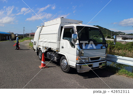 パッカー車 交通安全を見守るガードマンと収集車の写真素材