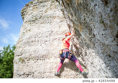 Photo from bottom of athletic woman in red helmet climbing a mountain 42654499