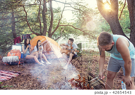Party, camping of men and women group at forest. They relaxing, singing a song and cooking barbecue 42654543