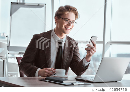 Young businessman in eyeglasses at office sitting drinking coffe 42654756