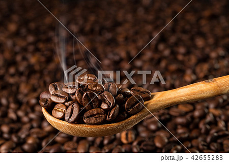 Roasted coffee beans in a wooden spoon, closeup Roasted coffee beans in a wooden spoon, closeup 42655283