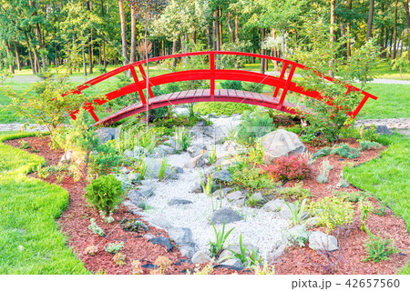 Red bridge above flowerbed in green park 42657560