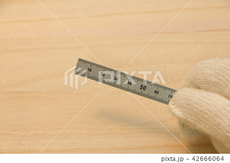 軍手をはめた手で持った金属製の定規(直尺)。 42666064