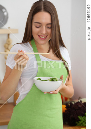 Young woman cooking in kitchen. Householding, tasty food and vegetarian in lifestyle concepts Young woman cooking in kitchen. Householding, tasty food and vegetarian in lifestyle concepts 42666199
