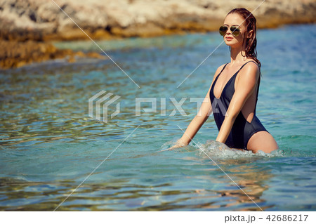 Pretty beautiful woman in white swimwear bikini posing in blue s 42686217