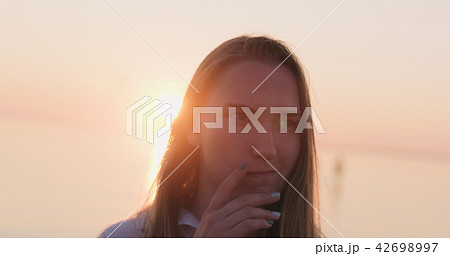 teenage girl standing on a beach at sunset and thinking about something 42698997
