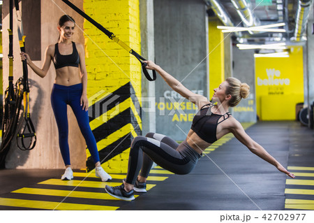 Two women are exercising with trx system in turn 42702977