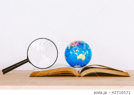 Global ball on book and  magnifying glass  42710571