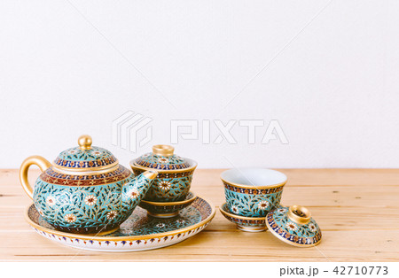Teapot with cup of tea on wooden table 42710773