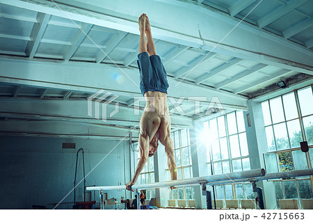 The sportsman during difficult exercise, sports gymnastics The sportsman during difficult exercise, sports gymnastics 42715663