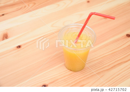 オレンジスムージーの入った飲み物のプラスチック容器とストロー 42715702