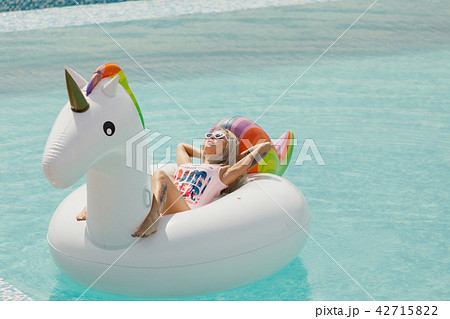 beautiful slim girl in a swimsuit. Floating on a big white beach inflatable unicorn pool beautiful slim girl in a swimsuit. Floating on a big white beach inflatable unicorn pool 42715822