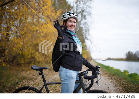 Photo of smiling brunette in helmet and with backpack showing ok on bicycle Photo of smiling brunette in helmet and with backpack showing ok on bicycle 42717439