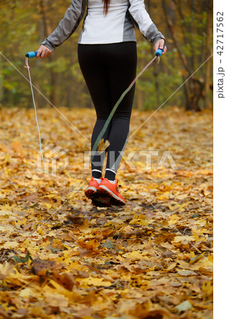 Photo from back of sports woman in sneakers jumping with rope 42717562