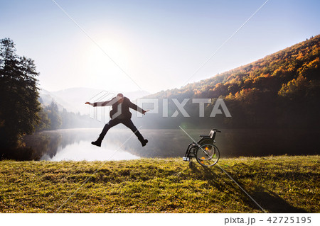 Senior man jumping by the wheelchair in autumn nature. Senior man jumping by the wheelchair in autumn nature. 42725195