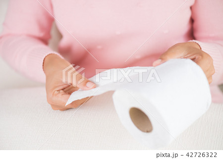 Woman hand pulling a white tissue from tissue roll 42726322