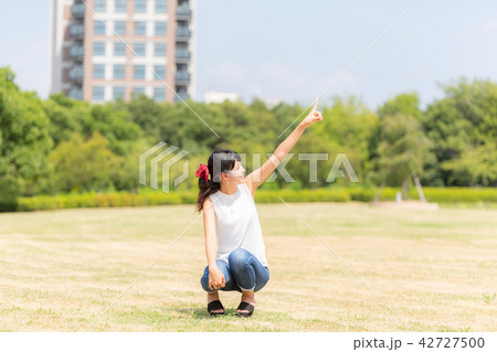 公園で空を指さす女性 42727500