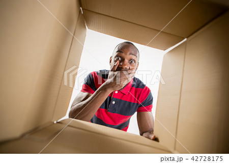 Man unpacking and opening carton box and looking inside 42728175
