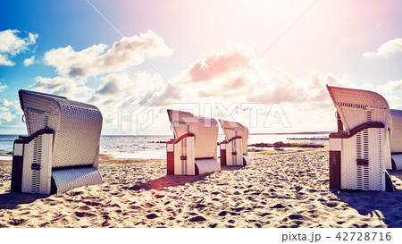Wicker hooded basket chairs on a beach at sunset. Wicker hooded basket chairs on a beach at sunset. 42728716