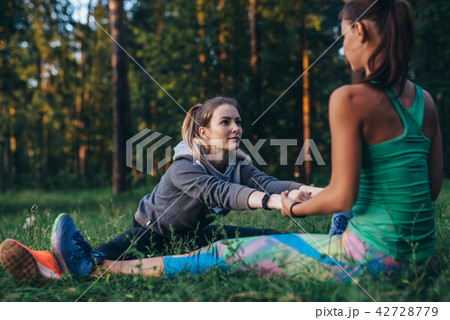 Two girls doing partner stretching yoga exercise, Paschimottanasana or seated forward bend pose 42728779