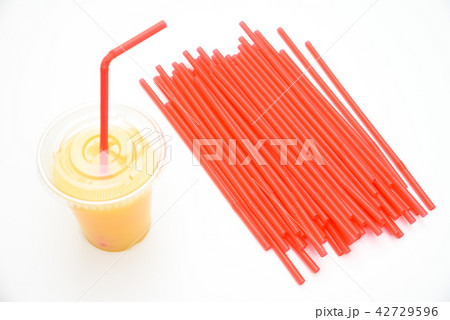 オレンジスムージーの入った飲み物のプラスチック容器とストロー 42729596