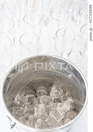 A metal ice bucket with full of crushed ice and stainless scoop for dessert on table in hotel. A metal ice bucket with full of crushed ice and stainless scoop for dessert on table in hotel. 42730996