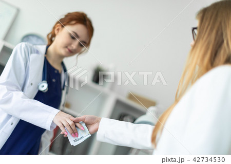 A beautiful young girl in a white robe is standing near a computer desk in the office and A beautiful young girl in a white robe is standing near a computer desk in the office and 42734530