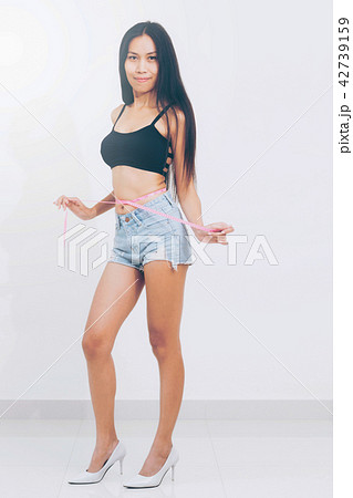 Slim woman measures her waist with measuring tape. 42739159