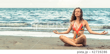 Young woman practices yoga on the beach in summer. Young woman practices yoga on the beach in summer. 42739286