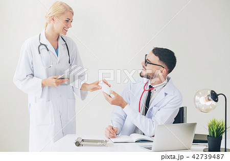 Doctor at hospital passes medicine to partner. 42739487
