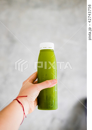 Woman's hand holds a bottle of green juice 42743756