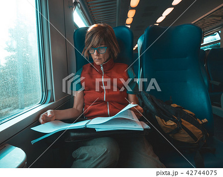 Woman using smart phone traveling by train Woman using smart phone traveling by train 42744075