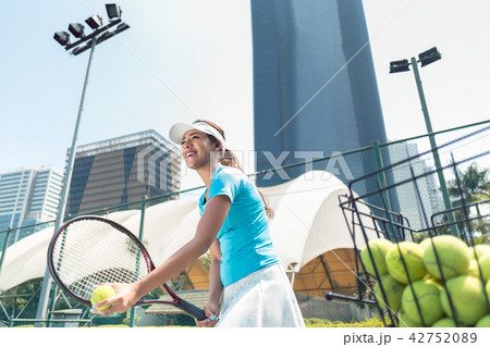 Cheerful beautiful woman playing tennis in a developed city Cheerful beautiful woman playing tennis in a developed city 42752089