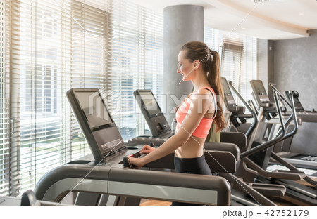 Young woman running on treadmills during workout Young woman running on treadmills during workout 42752179