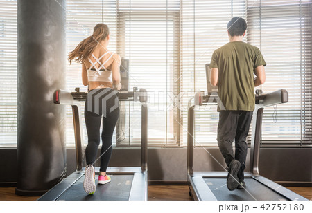 Young man and woman running on treadmills during workout Young man and woman running on treadmills during workout 42752180