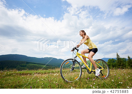 Attractive female cyclist with yellow mountain bicycle, enjoying sunny day in the mountains 42755885