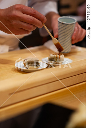 Professional sushi chef add final touch to sushi Professional sushi chef add final touch to sushi 42756140