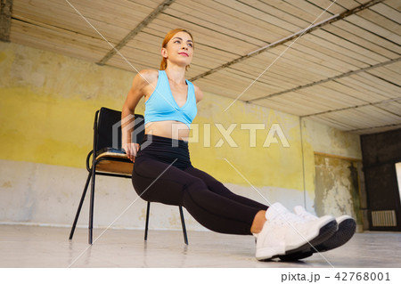 Woman doing physical exercise leaning on chair 42768001