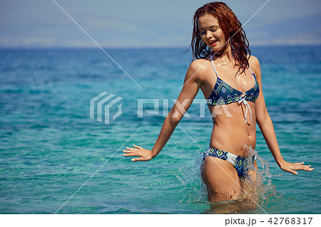 Pretty beautiful woman in white swimwear bikini posing in blue s 42768317