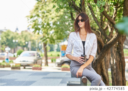 Front view of beatiful young student sitting on wooden bench. 42774585