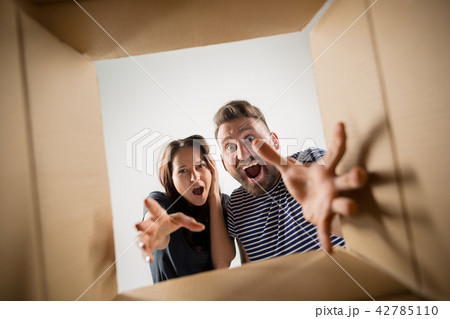 The couple unpacking and opening carton box and looking inside 42785110
