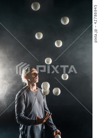Blond juggler with white balls on black background Blond juggler with white balls on black background 42786945